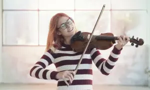 Dziewczyna w okularach z pasją gra na skrzypcach, czerpiąc radość z muzyki.
