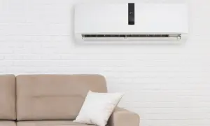 Condizionatore senza motore esterno come funziona: un'unità bianca a parete sopra un divano beige, con un display digitale che mostra 24 gradi.