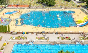 Tłum ludzi cieszy się słońcem i wodą w moczydło water park. Kolorowe zjeżdżalnie i baseny pełne są plażowiczów.