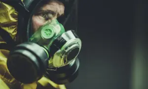 Osoba w żółtym kombinezonie ochronnym z maską, która stanowi sprzęt ochrony dróg oddechowych.