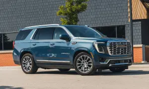 Niebieski GMC Yukon XL Denali lśni na tle nowoczesnej architektury.