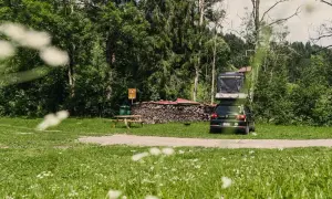 Campingplatz mit Dachzeltauto, Holzstapel und Picknicktisch. Ein idyllischer Ort für Basel Geheimtipps abseits des Trubels.