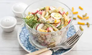 Salade de pâtes au surimi, œufs durs, concombre et radis, garnie d'aneth. Un délice frais et coloré.