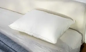 A plush white pillow rests on a neatly made bed, perfect for a comfortable night's sleep, especially for those who prefer to sleep on their stomach.