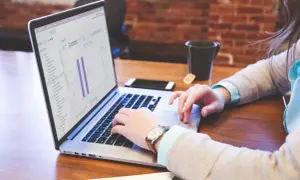Frau arbeitet am Laptop mit Statistiken, die auf eine effiziente Buchhaltung Gastronomie hindeuten.