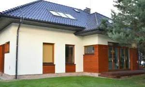 Nowoczesna **struktura elewacyjna** domu z białym tynkiem, drewnianymi panelami i dużymi oknami.