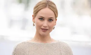 Jennifer Lawrence, gwiazda wielu filmów, w beżowym swetrze i złotych kolczykach.