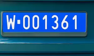 Niebieska tablica rejestracyjna z białymi znakami: W-001361.