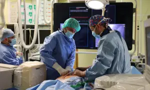 Chirurdzy w maseczkach i fartuchach podczas operacji na sali zabiegowej.