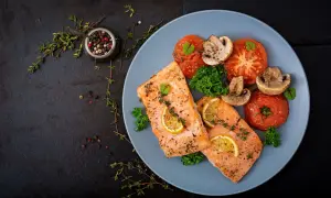 Dwa filety łososia z cytryną i ziołami, podane z pieczonymi pomidorami i pieczarkami. Zdrowe gotowanie na parze w najlepszym wydaniu.