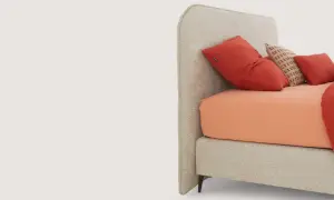 Lit moderne avec tête de lit capitonnée, drap orange vif et coussins rouges. Idées pour comment fixer tête de lit.