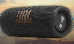 Enceinte JBL noire sur une plage. Découvrez comment fonctionne une enceinte JBL pour une expérience sonore immersive, même en extérieur.