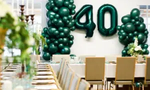 Uroczyste przyjęcie z okazji 40 urodzin. Zielone balony tworzą liczbę 40. Stół nakryty do eleganckiej kolacji.