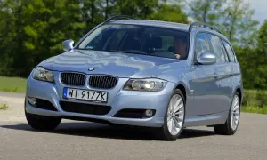 Błękitne BMW E91 na drodze, widać wyraźnie jego przednie światła i grill.