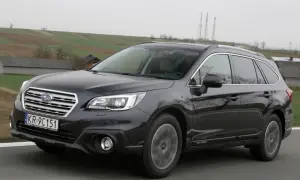 Ciemnoszary Subaru Outback 2025 na tle wiejskiego krajobrazu.