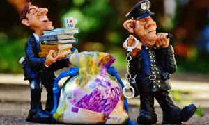Figurki policjanta z kajdankami i mężczyzny z książkami i torbą pieniędzy.