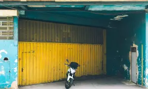 Moto aparcada frente a una cochera con puerta amarilla, se puede aparcar en una cochera sin vado.
