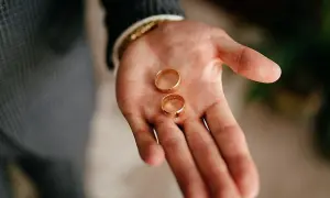Dos anillos de oro descansan en una mano abierta, listos para ajustar el anillo y sellar un compromiso.