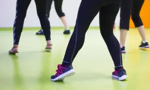 Ludzie w legginsach i butach sportowych ćwiczą na sali. Może właśnie dlatego buty skrzypią?