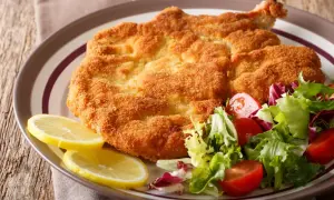 Chrupiący kotlet milanese z cytryną i świeżą sałatką z pomidorkami.
