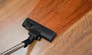 Cabezal de aspiradora limpiando suelo laminado. El suelo laminado se ve brillante y limpio tras pasar la aspiradora.