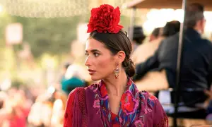 Mujer con flor flamenca en su pelo corto, pendientes llamativos y mantón bordado.