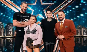 Cztery osoby stoją na scenie z gwiazdą w tle. To jury Mam Talent.