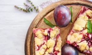 Saftiger Zwetschgenkuchen vom Blech mit Streuseln, garniert mit frischen Pflaumen und Minze.