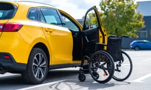 Auto gialla con portiera aperta e carrozzina. Informazioni su quanto costa passaggio di proprietà auto con legge 104.