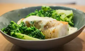 Un plat de queue de lotte poêlée, nappée d'une sauce crémeuse et accompagnée de brocolis croquants.