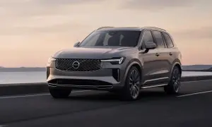 Elegancki, szary Volvo XC90 jedzie po drodze nad morzem. Sprawdź aktualną volvo xc90 cena i wybierz swój wymarzony SUV.