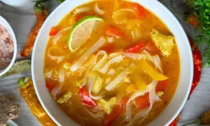 Aromatyczna zupa z makaronem ryżowym, z kawałkami kurczaka, papryki i plasterkiem limonki.