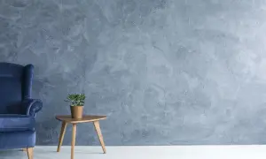 Fauteuil bleu profond devant un mur texturé en **stucco mur**. Une petite plante verte repose sur une table d'appoint en bois.