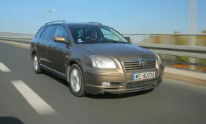 Brązowy Toyota Avensis T25 w kombi jedzie po drodze. Widać przednie żarówki i tablicę rejestracyjną WE 80036.
