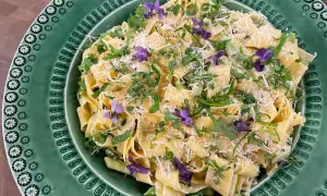 Krämig sparris pasta med färska örter och violblommor, toppad med riven parmesan. En härlig vårrätt!