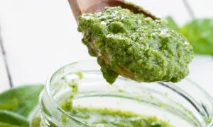 Frisch zubereitetes Basilikum-Pesto auf einem Holzlöffel, bereit für das Einmachen. Ein tolles Rezept für Basilikum-Pesto auf Vorrat.