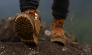 Solidne buty w góry z pomarańczowymi sznurówkami na kamienistym szlaku.