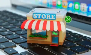 Miniatura de una tienda en línea sobre un teclado de portátil. La tienda tiene un letrero de "STORE", toldo a rayas y un cartel de "OPEN".