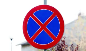 Znak drogowy informujący o zakazie postoju. Czerwone X na niebieskim tle.