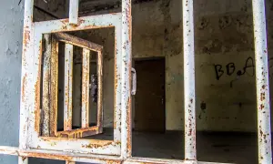 Grille rouillée d'une cellule abandonnée, porte ouverte. Un vestige de l'urbex à Laval, où le passé murmure.