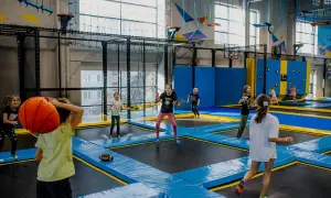 Dzieci skaczą na trampolinach, rzucają piłką i grają w gry. Wspaniałe zabawy na 30 urodziny w parku trampolin.