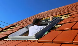 Pracownik montuje małe okienko w dachu, które zapewni światło.