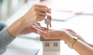 Un asesor compra vivienda entrega las llaves de una casa modelo a un cliente.