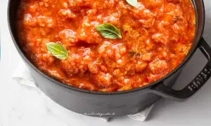 Pappa al pomodoro fumante in una pentola scura, guarnita con foglie di basilico fresco. Un classico comfort food toscano.