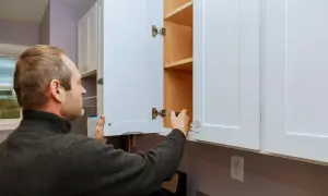 Hombre ajustando bisagras para como regular puertas de armario.