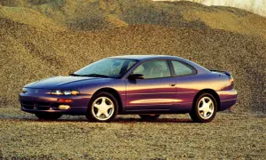 Fioletowy Dodge Avenger z lat 90. stoi na tle żwirowych wzgórz.