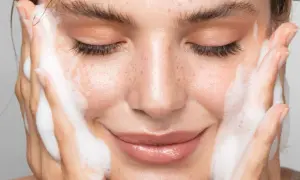 Visage de femme aux yeux fermés, profitant d'un nettoyage en profondeur avec de la mousse sur les joues.