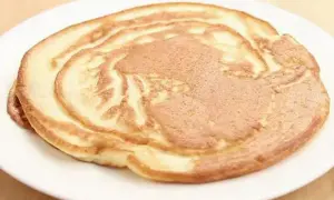 Ein goldbrauner Pfannkuchen ohne Ei auf einem weißen Teller, perfekt für ein leichtes Frühstück.