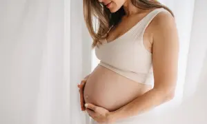 Gravid kvinna med händer på magen, mjukt ljus. Hon kanske använder bio oil gravid för att ta hand om sin hud.