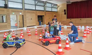 Kinder lernen spielerisch Verkehrsregeln bei der Verkehrserziehung im Kindergarten. Kleine Autos und Pylonen simulieren eine Straße.
